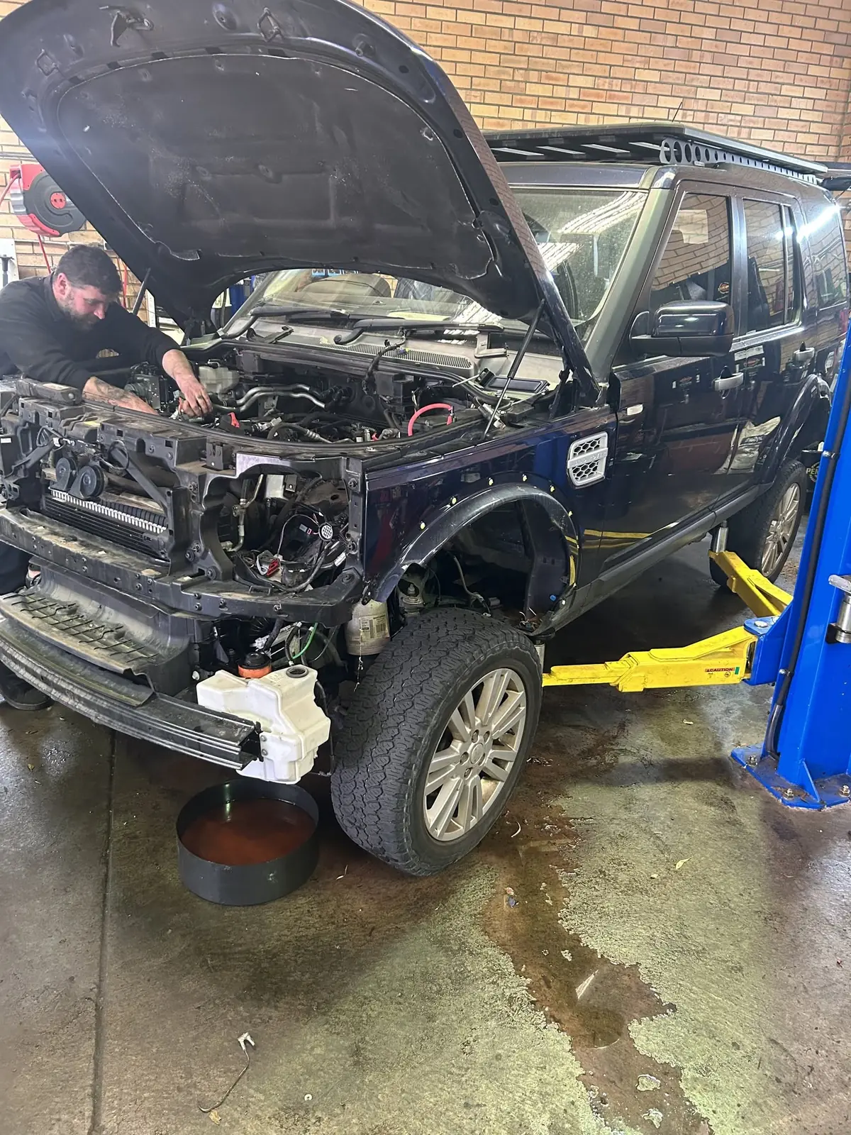 Discovery 4 on a hoist in the Jordan Rover-Tech workshop with the front end stripped for repair